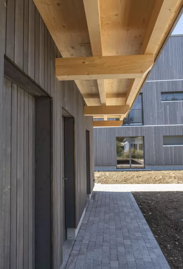 Mehrfamilienhaus Truberholzhaus Recherswil, Schweizer Holz, Truberholzwände sind nicht sichtbar, die Dübel sind nicht sichtbar, Fassade ist vorvergraut, es hat eine Attikawohnung, im Erdgeschoss und Obergeschoss hat es Loggaeinschnitte (Terrasse, Balkon), moderner Neubau, auf dem Dach ist ein Sonnensegel, Flachdach mit Solarpanel, es hat kein Keller dafür ein zusätzliches Gebäude mit Autounterstand und Lagerraum, Umschwung mit Rasen