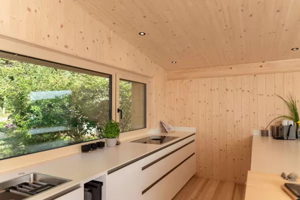 Truberholz Einfamilienhaus mit integrierter Arven-Täfer Wand. Schlafzimmer mit integrierter Dusche und Waschtisch. In der Dusche ist ein Brettstappel-Decke und der Boden ist aus ein Eschen Riemenboden. Die Wände sind Truberholz sichtbar. Die Decke ist leicht in der Dachschräge und ist eine Massivholzplatte. In der Wohnstube ist ein Cheminée mit Sitzoffen/Sitzbank.